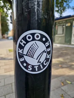 Street sticker A black and white round sticker with the text "EEKHOO STICKER" arranged in a circle around a simple graphic of a shopping cart and what looks like a pair of tongs or similar.