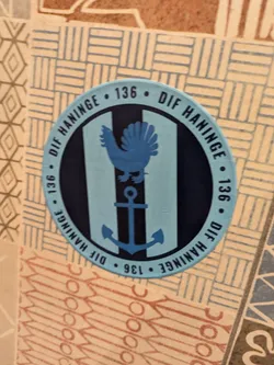 Street sticker Round sticker with the text "DIF Haninge 136" repeated around the edge.  Inside is a light blue circle with two vertical dark blue stripes. A blue rooster is above a blue anchor in the center.