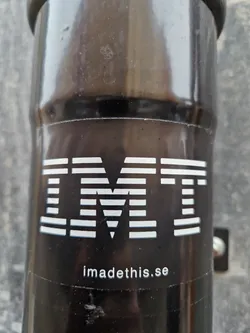 Black and white sticker with the text IMT and the website imadethis.se. The sticker is attached to a black cylindrical object.