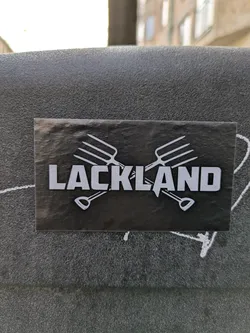Street sticker A black sticker shows the word "LACKLAND" in bold white letters, set against two crossed gardening tools - a garden fork and a shovel.