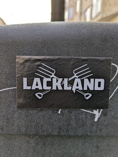 Street sticker A black sticker shows the word "LACKLAND" in bold white letters, set against two crossed gardening tools - a garden fork and a shovel.