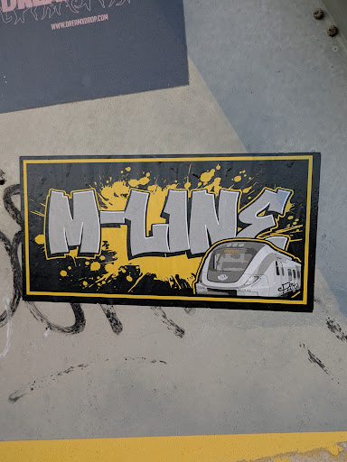 Street sticker A sticker featuring graffiti-style lettering of 'M-Line' with a train illustration. The design incorporates a yellow and black color scheme with paint splatters.