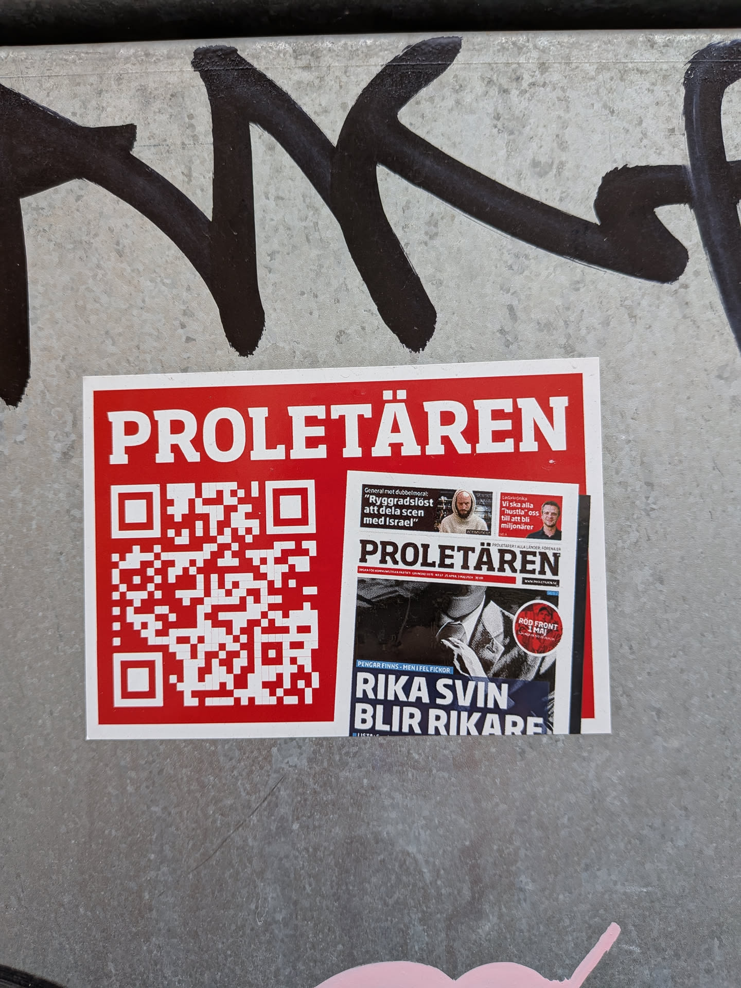 A rectangular sticker with a red background and a white border. The top displays the title 'PROLETÄREN' in bold white capital letters. The left side features a large red and white QR code, while the right side shows a miniature image of the newspaper's front page, featuring headlines such as 'RIKA SVIN BLIR RIKARE' and a 'RÖD FRONT 1 MAJ' badge.