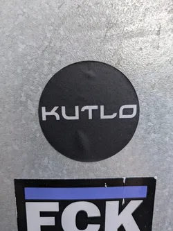 Street sticker A round black sticker with the word KUTLO in white sans-serif uppercase letters. 