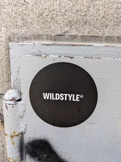 Street sticker A black circular sticker with the word WILDSTYLE in white text on a weathered metal surface.