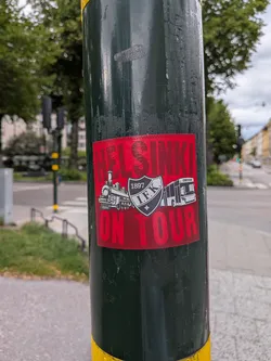 Street sticker A red rectangular sticker featuring the bold text 'HELSINKI ON TOUR'. The center displays the black and white HIFK crest (1897 I.F.K.) flanked by a steam locomotive on the left and a bus on the right.