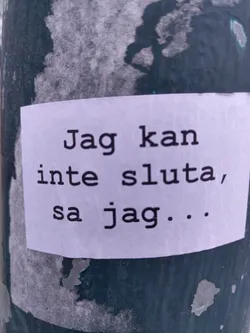 Street sticker A white sticker with a simple text message in Swedish.  The text appears to be typed and looks like a personal thought or statement. The sticker is affixed to a dark-colored pole outdoors, showing some wear and tear.
