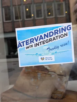 Street sticker Rectangular sticker featuring a passenger airplane against a blue sky. Text reads 'ÅTERVANDRING INTE INTEGRATION' and 'Trevlig resa!'. Includes the 'Alternativ för Sverige' party logo with a heart-shaped Swedish flag.