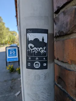 Street sticker A rectangular, black and white sticker designed to resemble a smartphone screen. At the top left, there's a small 'Cancel' button. Below this, a white silhouette of a cityscape with a prominent dome and a tower, against a black background, with a few small birds flying. The central feature is large, stylized, dripping white graffiti text that appears to spell 'Cesc'. Below the graffiti, there's a row of small white icons: a grid, a refresh/rotate symbol, and a lightning bolt. At the bottom, a larger, prominent white Instagram camera logo is centered, flanked by a smaller camera icon to its right.