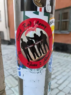 Round sticker with a red background featuring silhouettes of people against a backdrop of a red flare or smoke. Text on the sticker includes 'Black Red Army', 'Gate 2 Admission', and partially visible text that seems to say 'Arena Wacker'. The numbers '20' and '15' are visible on either side of the design. 