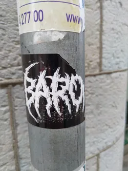 Street sticker Black and white sticker with the word BARON in a stylized font. The letters have sharp, jagged edges, giving it a metal or gothic look.  The sticker is affixed to a gray metal pole.