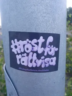 A purple sticker on a grey pole with the text "röst för rättvisa" which translates to "vote for justice" in Swedish. The sticker has a stylized font and the Instagram handle @fridaysforfuture.stockholm is visible at the bottom.