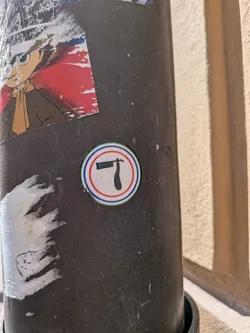 Street sticker A round sticker with a white background, depicting a black straight razor icon in the center. The icon is framed by concentric red, blue, and green circular borders.