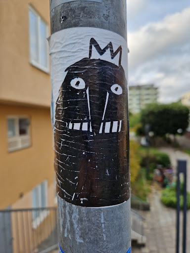 A black and white drawing of a monster with a crown. It looks like a simple, hand-drawn illustration with visible texture on the sticker.