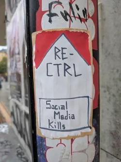 Street sticker A rectangular sticker designed to resemble a Marlboro cigarette pack. It features a red chevron shape at the top on a white background, with a tan border. The text 'RE-CTRL' is handwritten in black marker in the center. Below it, a hand-drawn black rectangle contains the warning 'Social Media Kills', mimicking tobacco health warnings.
