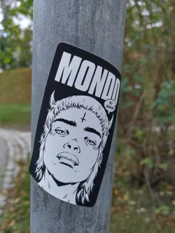 Street sticker Black and white sticker featuring a stylized illustration of a young person with devil horns and a cross on their forehead. The sticker has the word 'MONDO' prominently displayed at the top and 'BY KIMCHI' in a speech bubble.