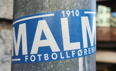 Street sticker A blue and white sticker on a metal pole.  The sticker features the text MALMÖ in large white lettering on a blue background, with the smaller text "1910" and "FOTBOLLFÖRENING" visible.
