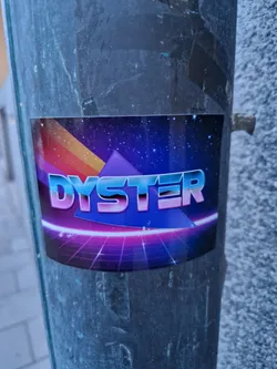 Street sticker A sticker featuring the word 'DYSTER' in a stylized 80s-inspired font. The design incorporates a vibrant color scheme of purples, blues, and pinks, along with a retro-futuristic grid pattern reminiscent of synthwave aesthetics. The overall style is reminiscent of 1980s graphic design and video game art.