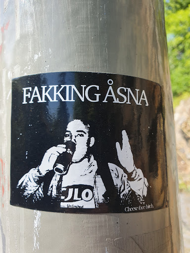 Street sticker Black and white sticker featuring a person drinking from a cup and making a hand gesture. The text "Fakking Åsna" is at the top and "Cheese face bitch" at the bottom.