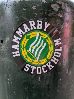Street sticker A circular sticker featuring the Hammarby Stockholm logo, consisting of a green and white emblem surrounded by a golden laurel wreath and the text "HAMMARBY STOCKHOLM" in white lettering on a black background.