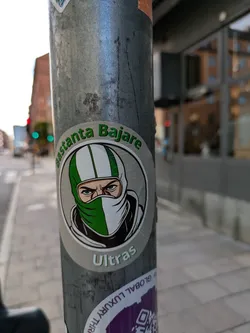 Street sticker A sticker featuring an illustration of a person wearing a balaclava with green and white stripes. The text "Bastanta Bajare" is written above the illustration, and "Ultras" is written below it.