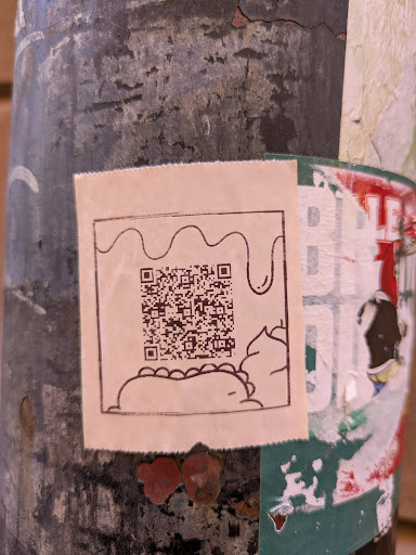This sticker features a quirky design with a hand-drawn style. At the bottom is a simple illustration of a taco or burrito, topped with some sort of sauce. Above the taco is a QR code.