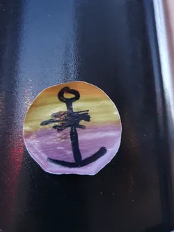 Street sticker A small, round sticker featuring a simple drawing of an anchor. The anchor is black, and the background is a gradient of yellow, orange, and purple, reminiscent of a sunset.  The style is child-like or naive.