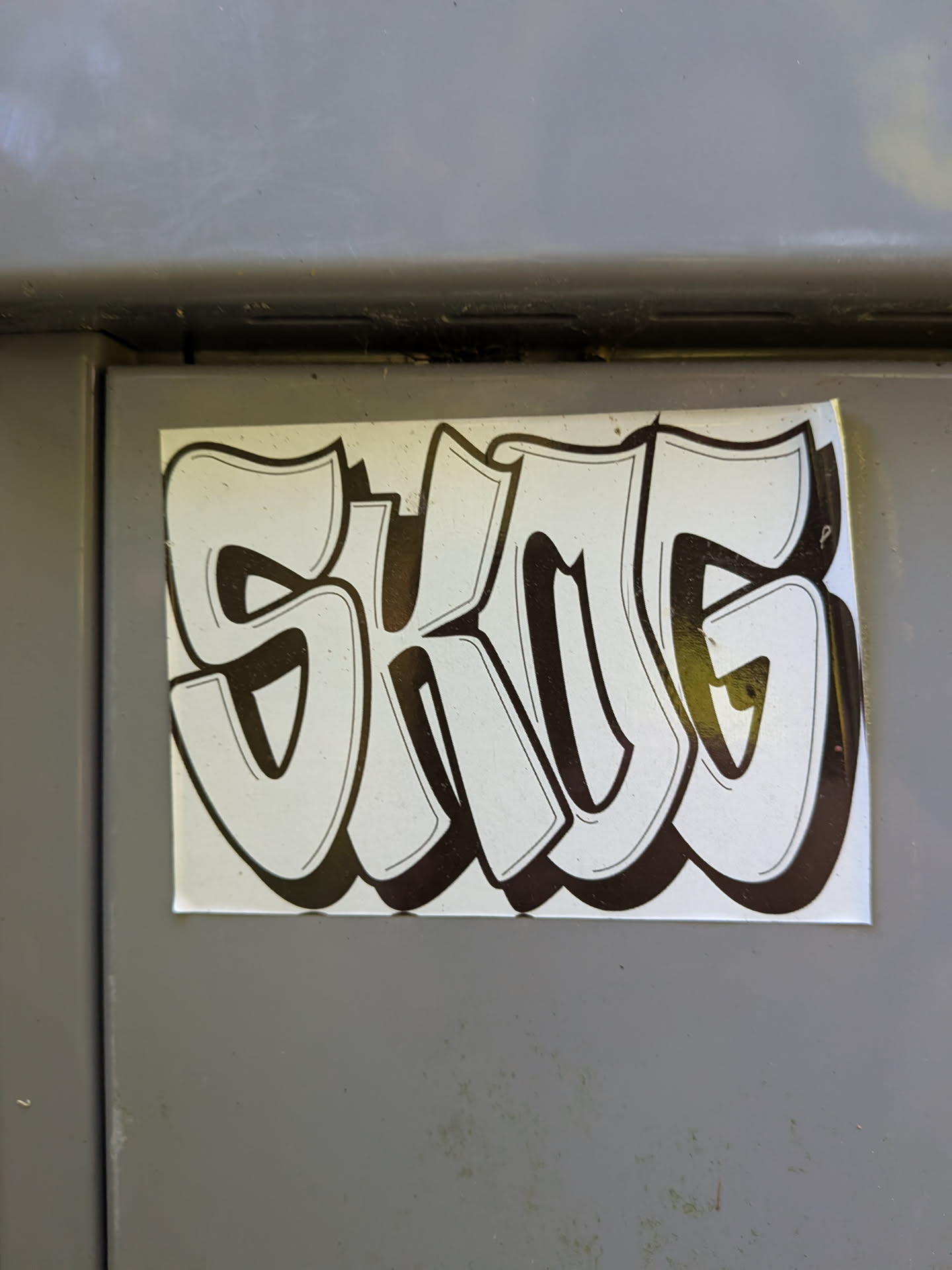 Rectangular white sticker featuring the word 'SKOG' in stylized graffiti bubble letters with thick black outlines and heavy drop shadows.