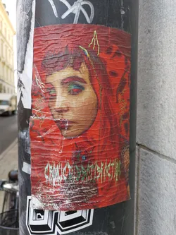 Street sticker A sticker featuring a stylized portrait of a woman with vibrant makeup against a red background. The text "CHRONIC DISSATISFACTION" is visible at the bottom. The sticker shows some signs of wear and tear.