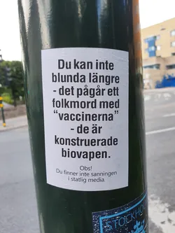 A sticker on a pole with a text in Swedish claiming that vaccines are bioweapons and that the truth cannot be found in mainstream media.