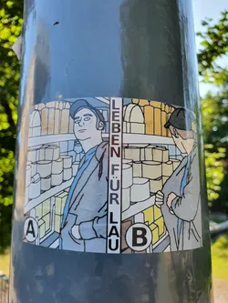 Street sticker A sticker featuring an illustration of two individuals in a supermarket setting. The text 'Leben für Lau' (Life for free) is prominently displayed. The artwork uses a simplistic, almost comic-like style.