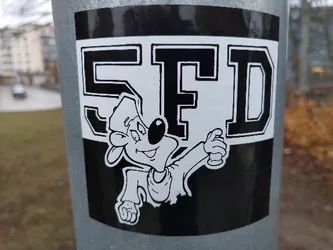 Street sticker Black and white sticker featuring a cartoon character holding a spray can, with the letters SFD prominently displayed.  The style is reminiscent of 90s hip-hop and graffiti culture. The sticker is affixed to a metal pole outdoors.