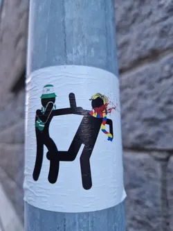 Street sticker This sticker shows a violent scene between two stick figures, one representing Celtic FC (based on the hat) and the other seemingly representing Romania (based on the scarf colors). The image is provocative and possibly alludes to political or football-related conflict.