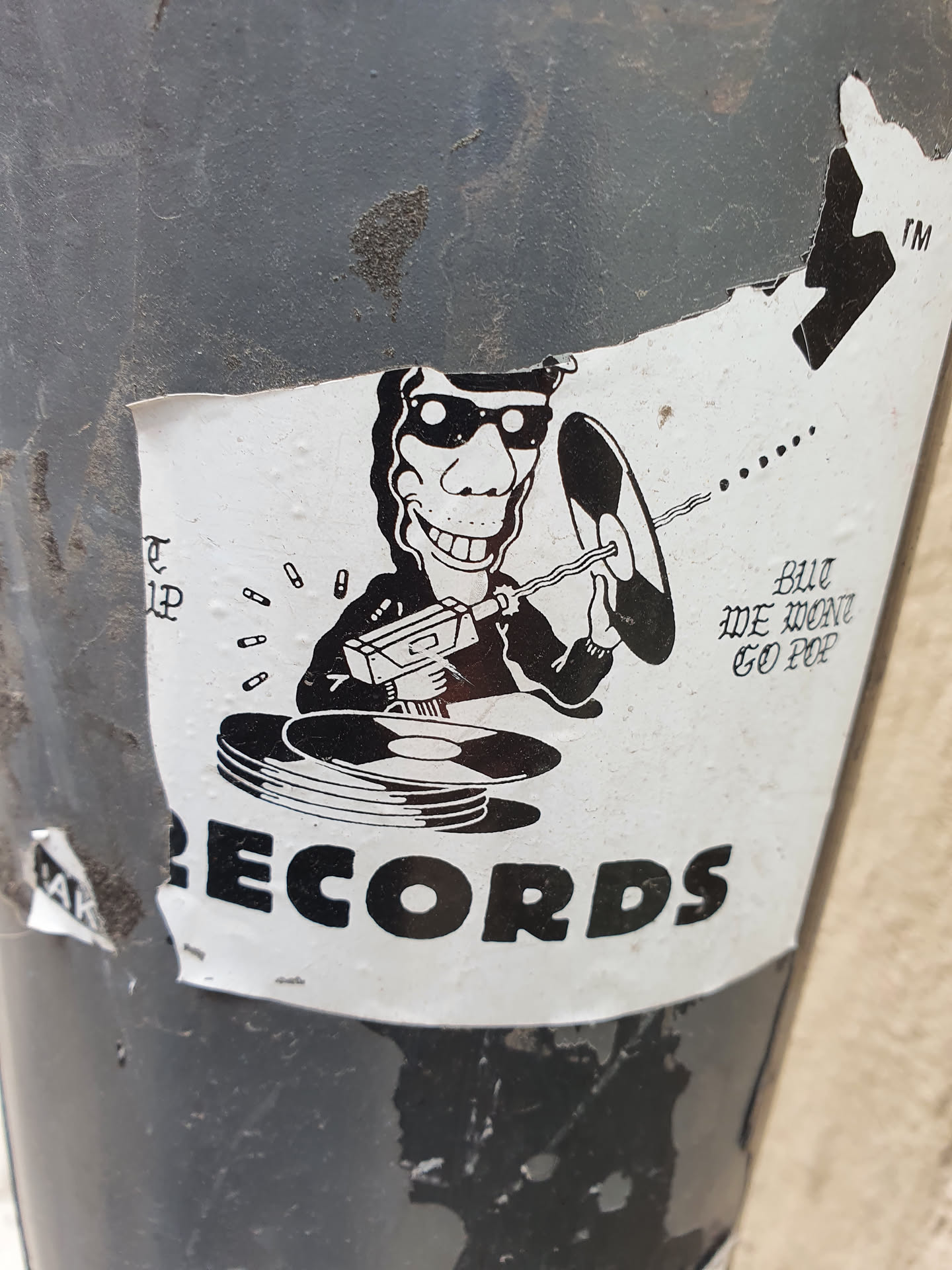 A black and white sticker with an illustration of a person with sunglasses using a drill on a record.  The word RECORDS is prominently displayed at the bottom. The text above states "BUT WE WANT GO POP".