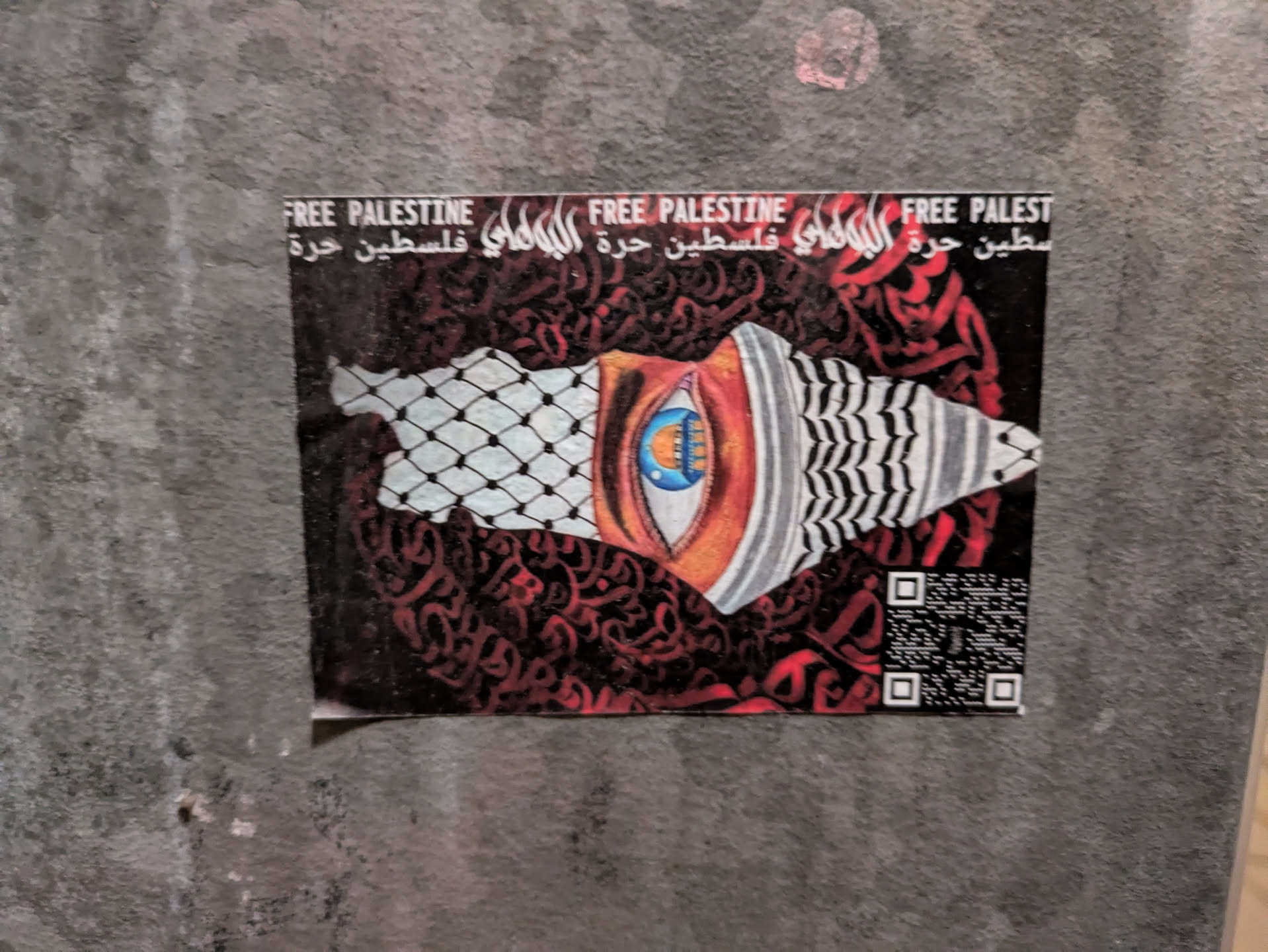 A sticker depicting a stylized eye and the map of Palestine, overlaid with Arabic calligraphy and a keffiyeh pattern. The text 'Free Palestine' is visible in both English and Arabic. A QR code is present in the bottom right corner.