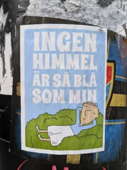 A sticker featuring a cartoon illustration of a person lying in the grass, with text in Swedish that translates to "No sky is as blue as mine." The style is simple and slightly humorous.