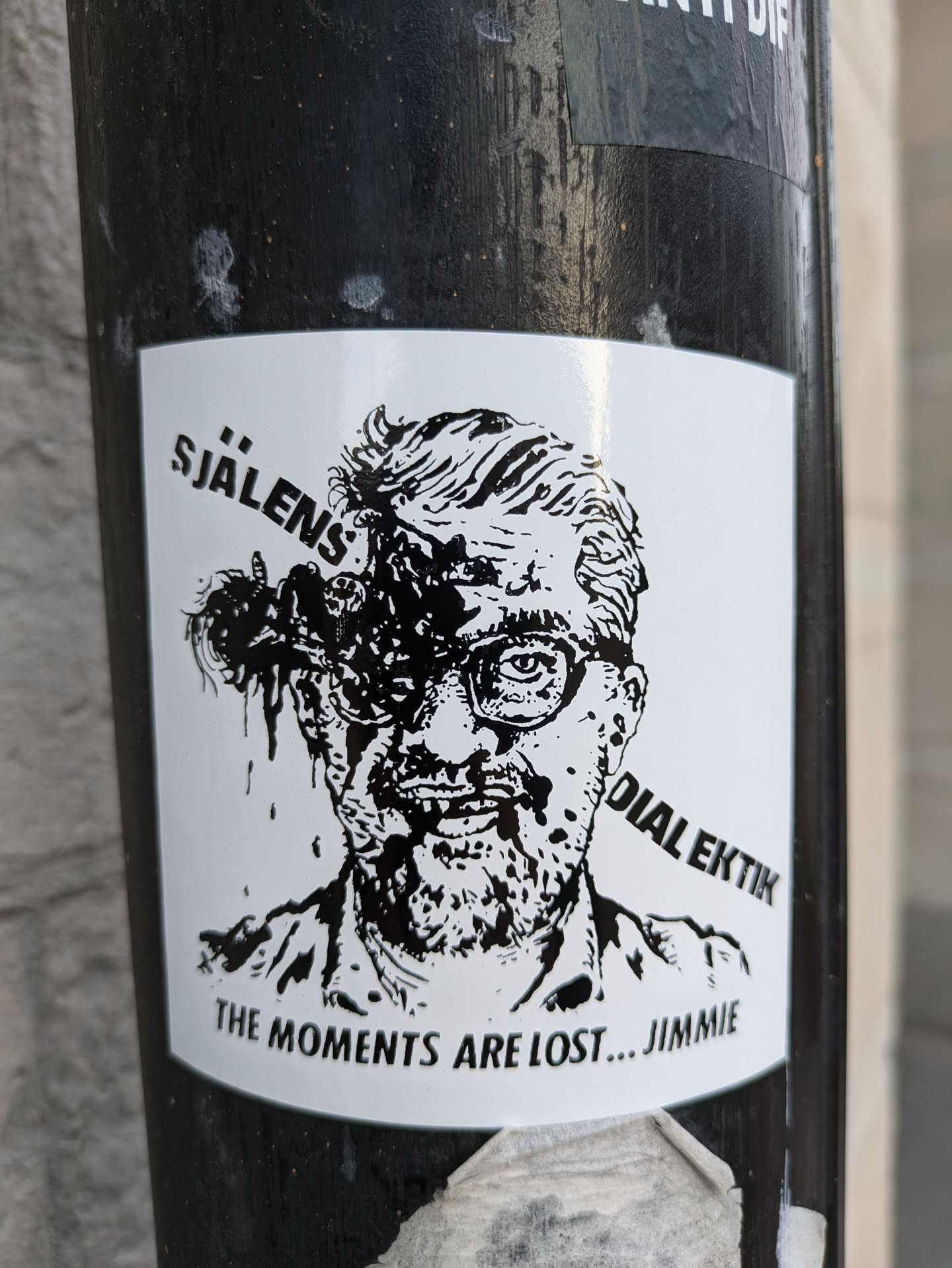 Black and white sticker featuring a stylized illustration of a man with glasses and a distressed appearance. Text on the sticker includes "SJÄLENS DIALEKIK" and "THE MOMENTS ARE LOST... JIMMIE".