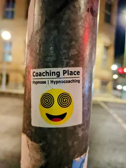 A sticker featuring a smiley face with hypnotic spirals for eyes. The text 'Coaching Place Hypnose | Hypnocoaching' is visible at the top.