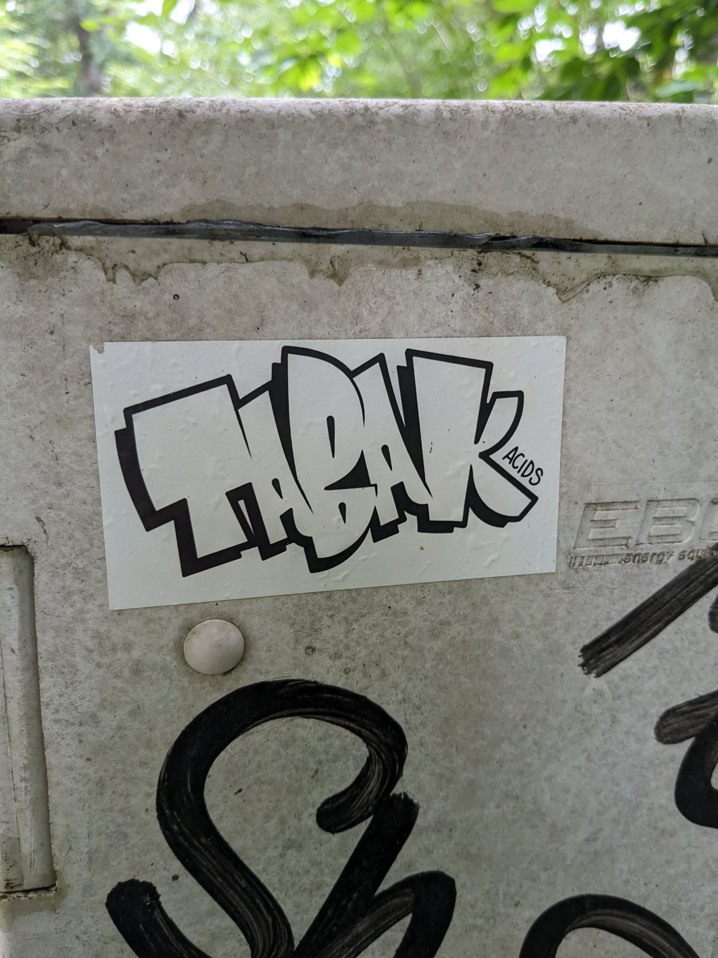 A rectangular sticker with black and white graffiti art. The word ThaBak is written in a stylized bubble letter font. In the bottom right corner, there is a small text that says ACID3.