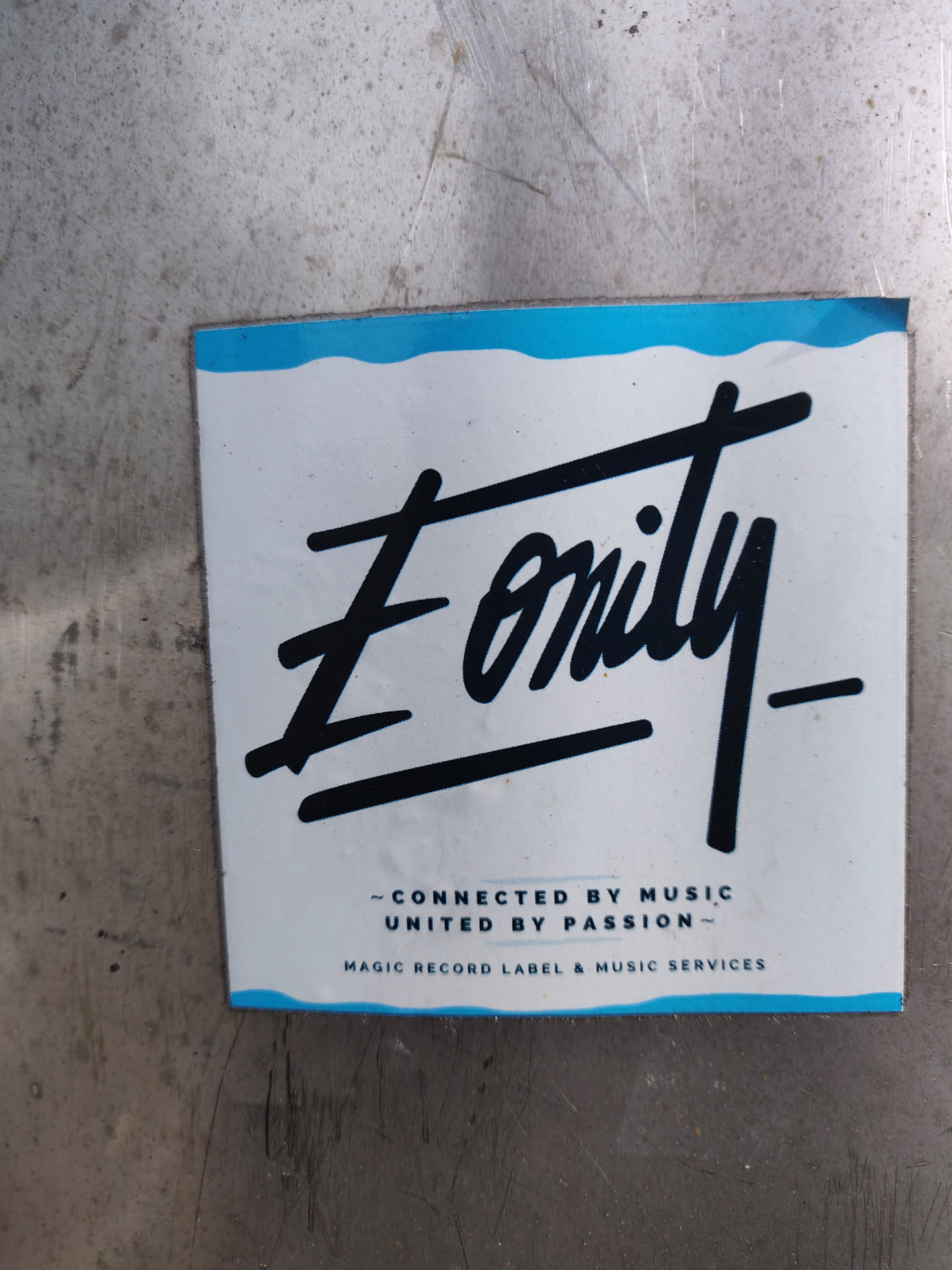 A sticker for the music label Eonity. The sticker has a white background with a blue wavy border and black text. The main text is the label's name 'Eonity' written in a stylized font. Below the name it says: - Connected by music, United by passion - and then in a smaller font: Magic record label & music services.
