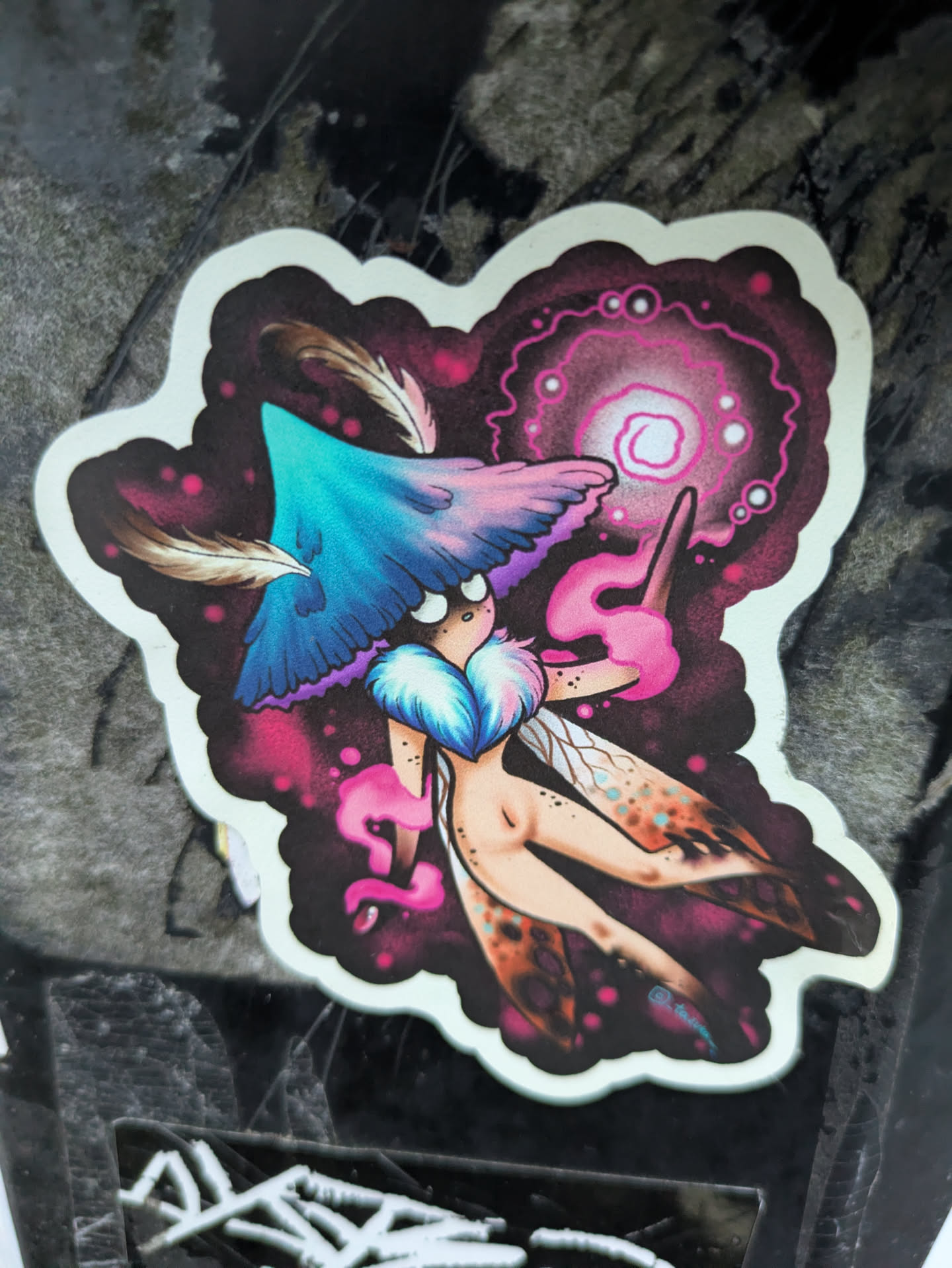 A vibrant sticker featuring a whimsical fairy with mushroom-like features, casting a spell with a glowing orb. The art style is dark fantasy with splashes of pink and purple.