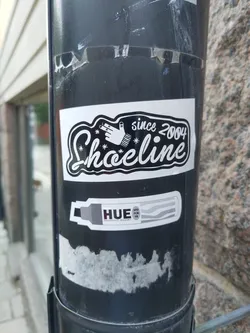 Black and white sticker with the text "Shoeline since 2004" and a hand graphic. There is also a smaller sticker underneath advertising HUE markers.