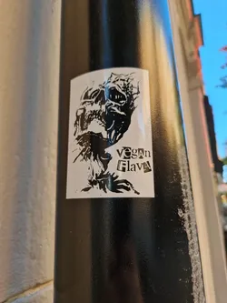 Black and white sticker featuring a skull with a screaming expression. The text "Vegan Flava" is visible on the bottom right corner.