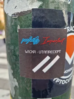 A dark-colored sticker with the text "perfectly Imperfect" in stylized fonts. The word "perfectly" is in light blue, and "Imperfect" is in red. Below the text, there is Wickr contact information: "WICKR : UTANRECEPT".  A simple logo of two parallel lines is present at the bottom. 