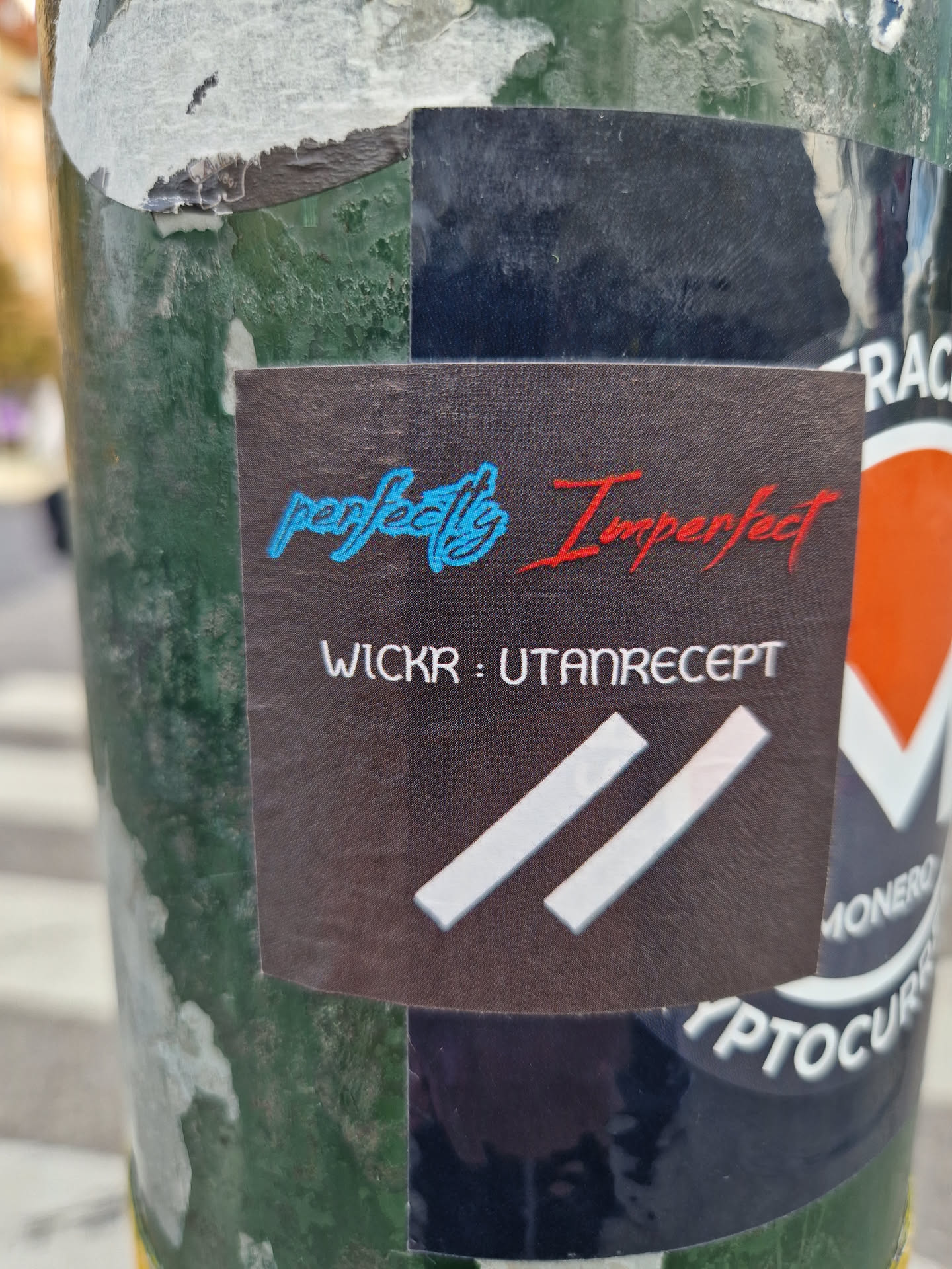 A dark-colored sticker with the text "perfectly Imperfect" in stylized fonts. The word "perfectly" is in light blue, and "Imperfect" is in red. Below the text, there is Wickr contact information: "WICKR : UTANRECEPT".  A simple logo of two parallel lines is present at the bottom. 