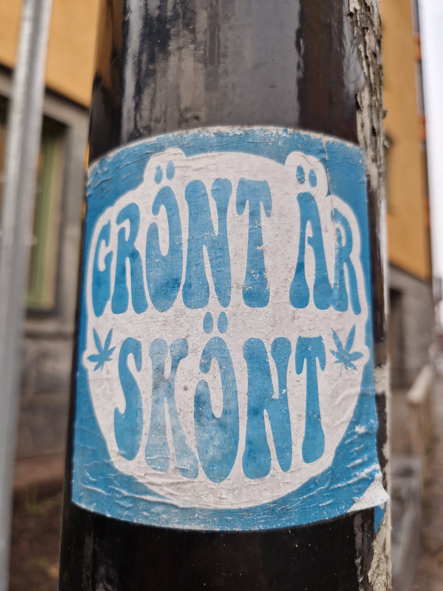 A blue and white sticker with the text "Grönt är skönt" (Swedish for "Green is nice") in a retro-style font.  The sticker features two stylized cannabis leaves.