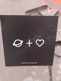 A black square sticker with white minimalist design. It features a planet symbol, a plus sign, and a heart, symbolizing the connection between humanity and Earth. The website letterfromhumanity.org is printed at the bottom.