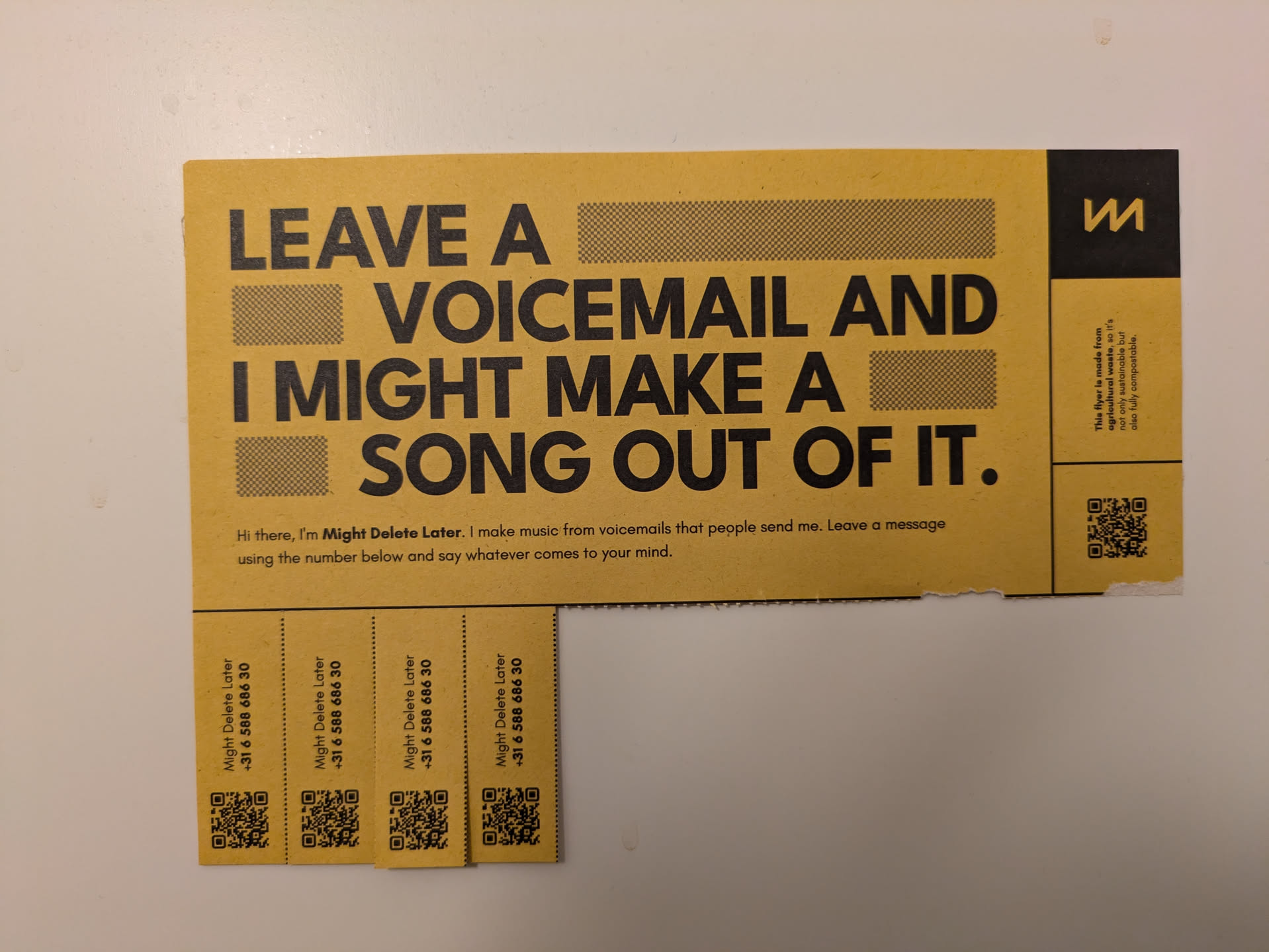 A yellow sticker with a bold message inviting people to leave a voicemail that might be turned into a song. It includes a phone number and QR codes.