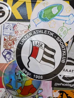Street sticker A round sticker featuring the logo of Linzer Athletik Sportklub (LASK), an Austrian football club. The logo includes a flag with red and black horizontal stripes. The text around the logo says "LINZER ATHLETIK SPORTKLUB" and "gegr. 1908", which means "founded in 1908".