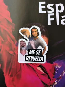 This sticker shows one man on top wearing headphones and another below. The text on the sticker reads "ME SE REVUELTA".